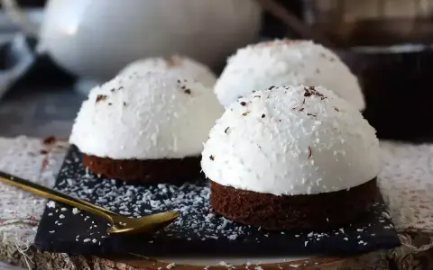 Tre små chokladbakelser med fluffig kokoskräm och strössel. En gyllene sked ligger redo för att njuta av dessa flan de coco.