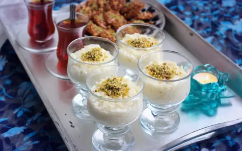 Fyra glas med krämig arroz en leche salvadoreño, toppad med pistagenötter. Två glas med te och en ljuslykta fulländar serveringen.