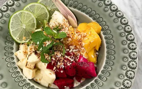 Fruktskål med mango, drakfrukt, banan, lime och mynta, toppad med rostad kokos. En härlig frukost som påminner om dulce de nance.