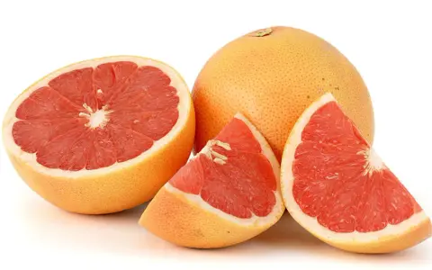 En hel och skivad rosa grapefrukt. Denna saftiga pomelo que es är en uppfriskande citrusfrukt.