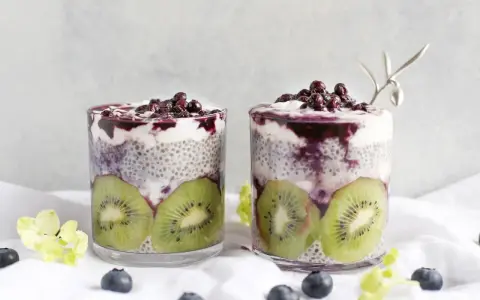 Två glas med chiapudding, kiwi och blåbär. En hälsosam frukost med nyttiga semillas de chia.