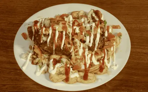 En tallrik med pollo chuco: friterad kyckling, stekta bananer, kål, tomat och majonnäs.