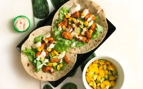 Två kycklingwraps med mango, avokado och sallad. En liten skål med mangosalsa. Hur många kalorier har en tortilla?