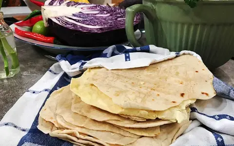 Färska tortillas de harina, redo att fyllas med goda ingredienser. I bakgrunden syns rödkål, chili och koriander.