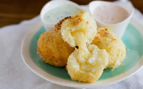 Krispiga papas rellenas de queso med smält ost som rinner ut. Serveras med två dippsåser.