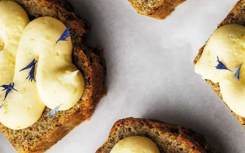 Skivor av saftig sockerkaka med fluffig citronkräm och blå blomblad. Perfekt för en fika, tack vare bakpulver som ger den luftiga konsistensen.