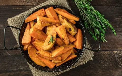 Ugnsrostad batata, eller sötpotatis, i en svart panna med rosmarin. En härlig rätt som visar vad que es batata.