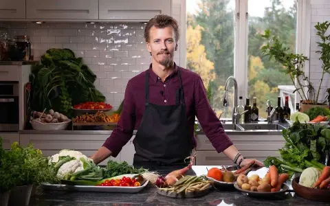 En kock i köket med ett överflöd av färska grönsaker, redo att visa olika tipos de cortes de vegetales.