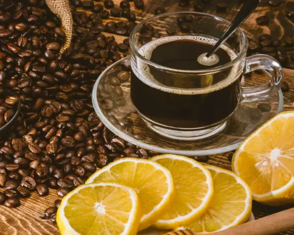 En kopp kaffe med citron, omgiven av rostade kaffebönor. En unik kombination för en café con limón-upplevelse.