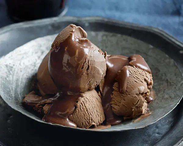 Tre kulor chokladglass, rikligt täckta med varm chokladsås, serveras i en rustik skål. En dröm för alla som älskar helado de chocolate.
