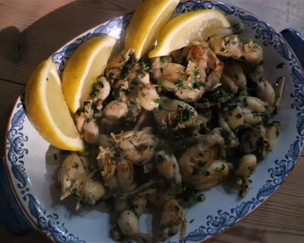 En skål med saftiga anas de rana, garnerad med citronklyftor och färska örter, redo att avnjutas.