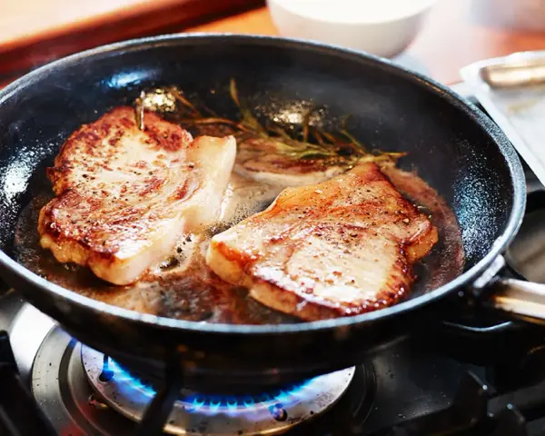 Två saftiga biffar steks i en panna med rosmarin. En perfekt guide för como hacer bistec de carne.