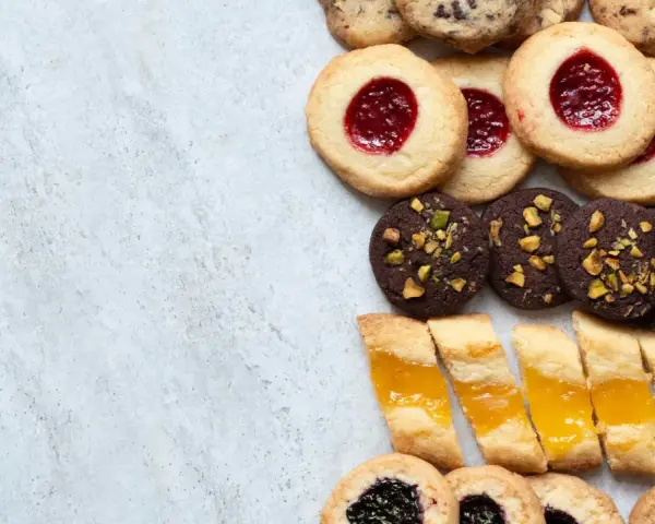 En variation av olika tipos de galletas: syltkakor, chokladkakor med nötter och småkakor med marmelad.