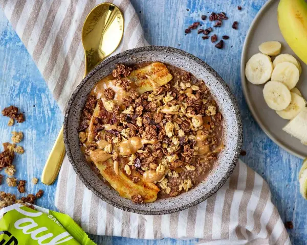 En skål med gröt, banan, granola och jordnötssmör. Perfekt för hälsosamma frukostar.