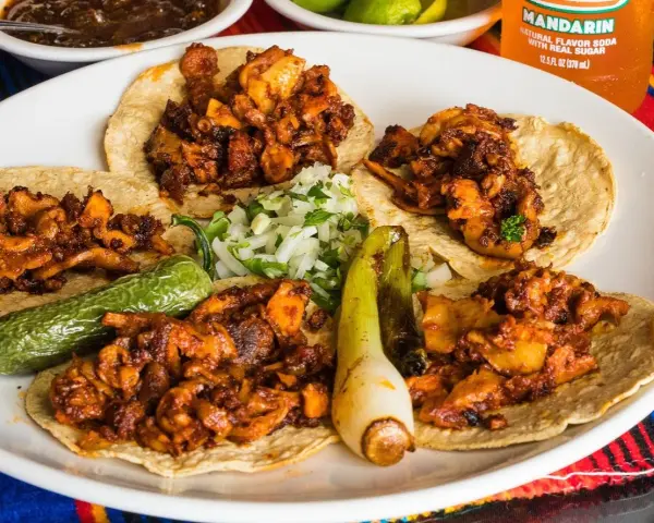 Fajitas de pollo con vegetales på en tallrik, med en läsk och salsa i bakgrunden.