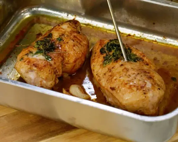Två saftiga kycklingbröst i en ugnsform, redo att serveras. Perfekt för dina **recetas de pollo**!