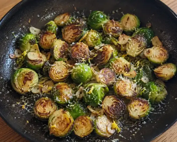 Stekta coles de bruselas med vitlök och parmesan i en gjutjärnspanna.