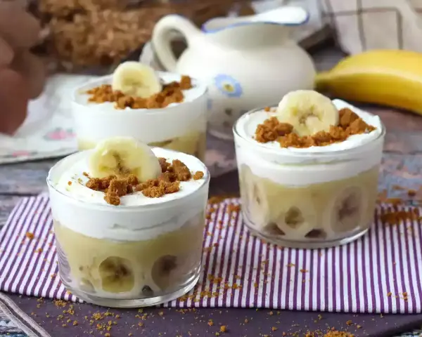 Tre små glas med bananpudding, vispad grädde och krossade kex. Platanos en gloria i sin dessertform.