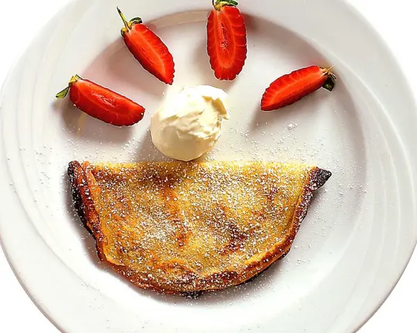 En glad pannkaka med jordgubbar och grädde. Crepas de fresa som ser ut som ett leende.