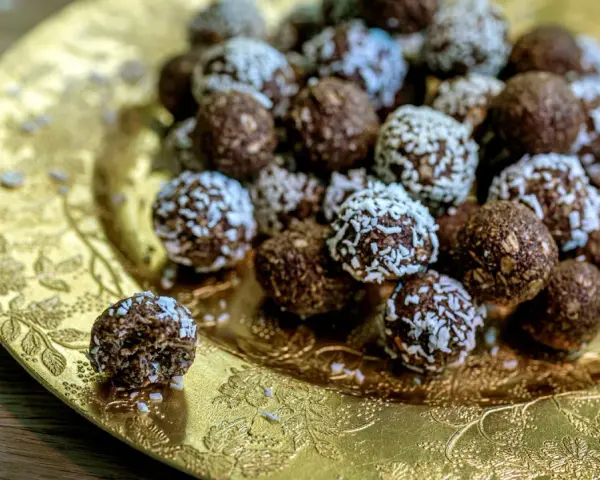 Chokladbollar med **harina de avena** (havregryn) på ett gyllene fat. En är uppäten.