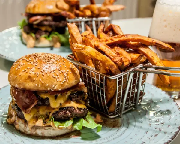 En saftig hamburguesa con papas frites i en korg, redo att avnjutas. En perfekt måltid för en hungrig själ.