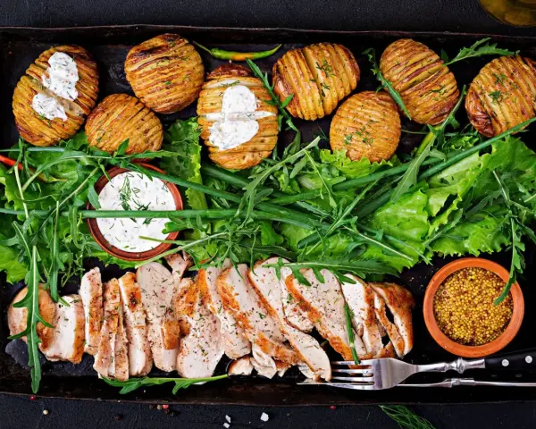 En härlig bricka med saftig kyckling, krispiga Hasselbackspotatisar och fräsch sallad. Perfekt för **cenas saludables y ligeras** – hälsosamma och lätta middagar.