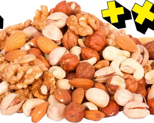 En hög med nötter, som mandlar, valnötter och pistagenötter, med gula kors i bakgrunden. Perfekt för en energiboost!
