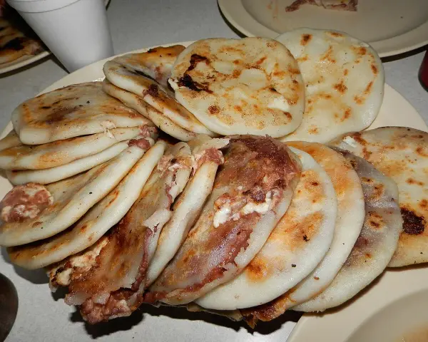 En tallrik med staplade pupusas salvadoreñas, gyllene och fyllda med läckra ingredienser.