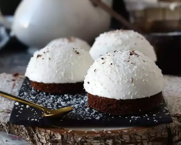 Tre små chokladbakelser med fluffig kokoskräm och strössel. En gyllene sked ligger redo för att njuta av dessa flan de coco.