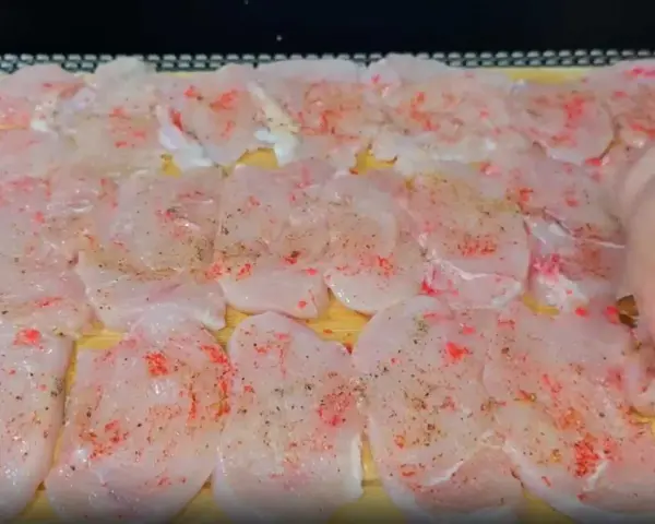 Tunna skivor av kyckling, kryddade med paprika och peppar, ligger redo att bli till saftiga medallones de pollo.