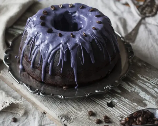 Mörk chokladkaka med lila glasyr och kaffebönor, ett härligt pastel de cafe.