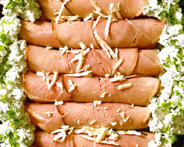 Rullade skinkskivor, enrollados de jamon, toppade med ost och serverade med en krämig ost- och gräslöksröra.