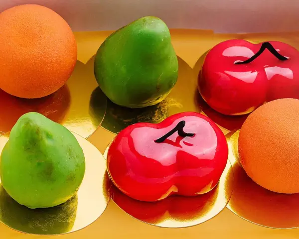 Sju glaserade bakverk i form av frukter: päron, körsbär och apelsiner. Dessa pasteles de frutas ser utsökta ut!