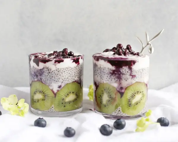 Två glas med chiapudding, kiwi och blåbär. En hälsosam frukost med nyttiga semillas de chia.