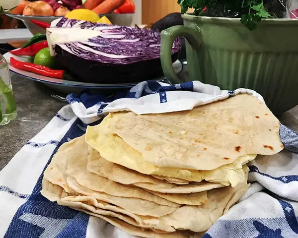 Färska tortillas de harina, redo att fyllas med goda ingredienser. I bakgrunden syns rödkål, chili och koriander.