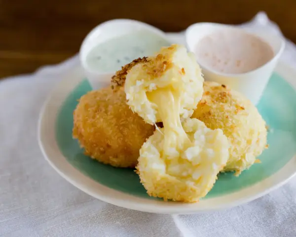 Krispiga papas rellenas de queso med smält ost som rinner ut. Serveras med två dippsåser.
