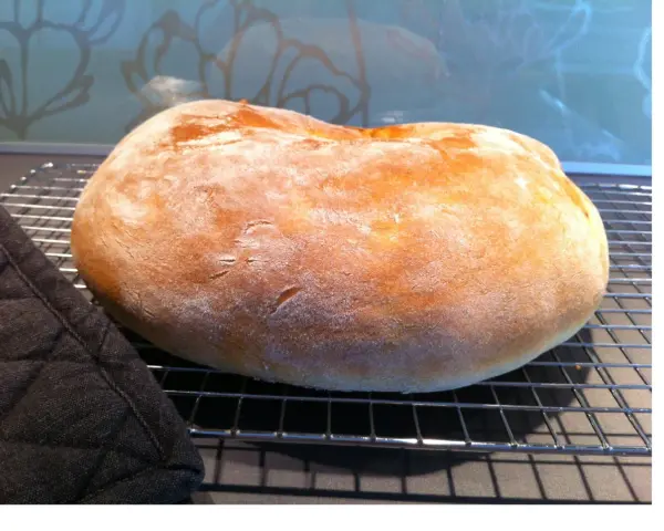 Ett nybakat, fluffigt **pan de torta** vilar på ett galler. En mörk grytlapp ligger bredvid.