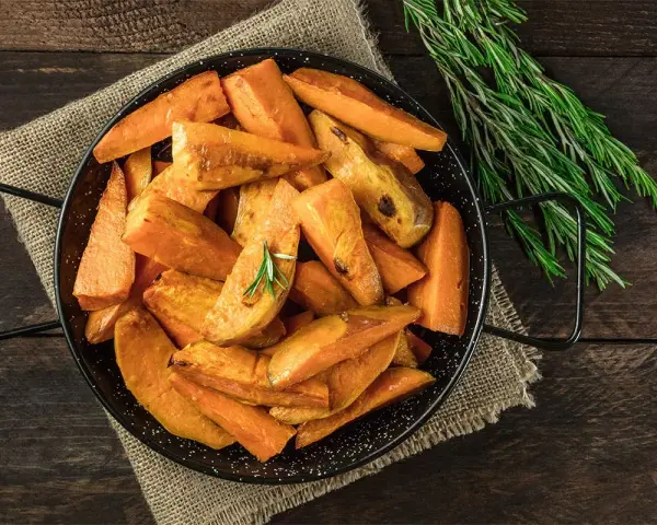 Ugnsrostad batata, eller sötpotatis, i en svart panna med rosmarin. En härlig rätt som visar vad que es batata.