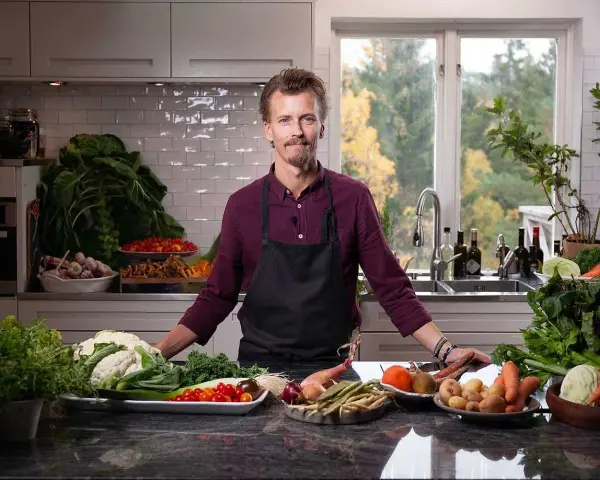 En kock i köket med ett överflöd av färska grönsaker, redo att visa olika tipos de cortes de vegetales.