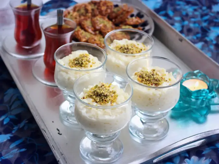 Fyra glas med krämig arroz en leche salvadoreño, toppad med pistagenötter. Två glas med te och en ljuslykta fulländar serveringen.