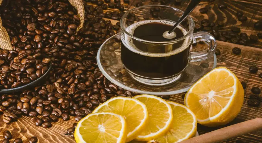 En kopp kaffe med citron, omgiven av rostade kaffebönor. En unik kombination för en café con limón-upplevelse.