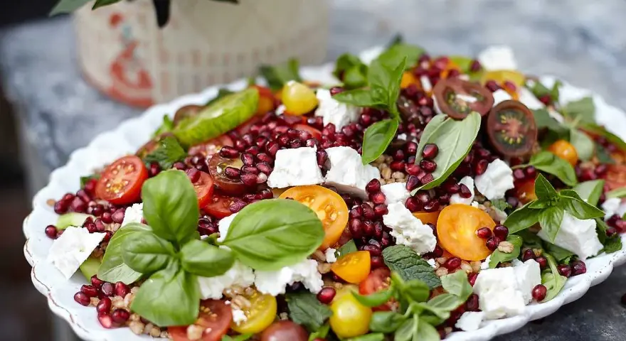 En färgstark sallad med granatäpple, tomater, fetaost och basilika. Perfekt för att visa para qué sirve la ensalada – en hälsosam och god måltid!