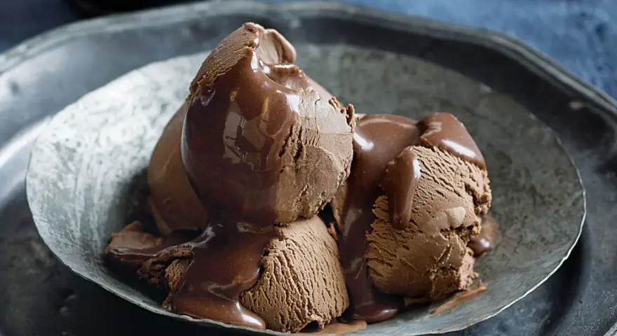 Tre kulor chokladglass, rikligt täckta med varm chokladsås, serveras i en rustik skål. En dröm för alla som älskar helado de chocolate.