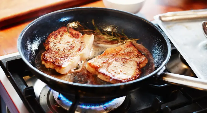 Två saftiga biffar steks i en panna med rosmarin. En perfekt guide för como hacer bistec de carne.