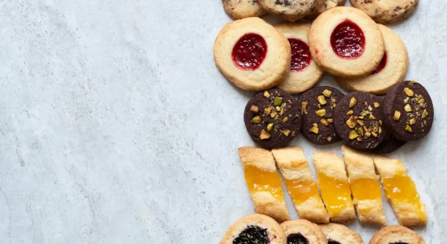En variation av olika tipos de galletas: syltkakor, chokladkakor med nötter och småkakor med marmelad.