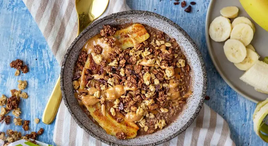 En skål med gröt, banan, granola och jordnötssmör. Perfekt för hälsosamma frukostar.