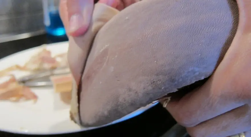 En hand håller en lengua de vaca, en del av en ko-tunga, redo att tillagas.
