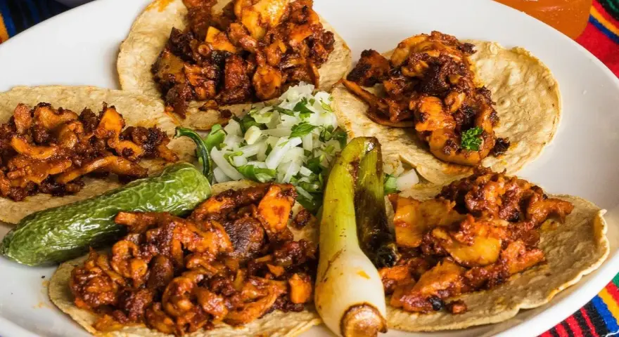 Fajitas de pollo con vegetales på en tallrik, med en läsk och salsa i bakgrunden.