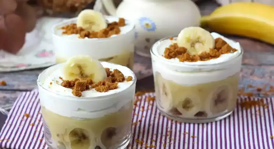 Tre små glas med bananpudding, vispad grädde och krossade kex. Platanos en gloria i sin dessertform.