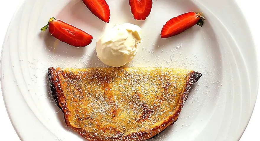 En glad pannkaka med jordgubbar och grädde. Crepas de fresa som ser ut som ett leende.